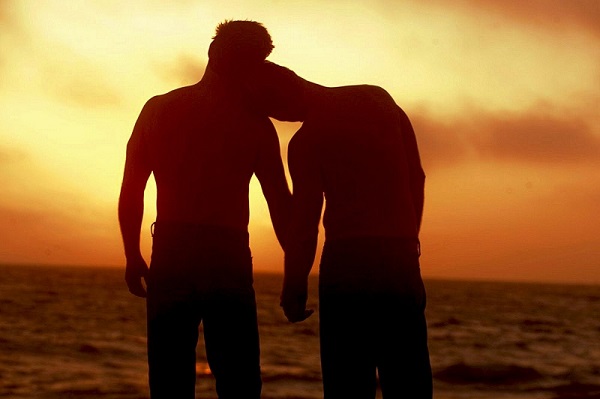 two-men-on-the-beach-at-sunset-holding-hands